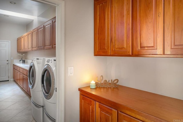 washroom featuring washing machine and dryer, cabinets, and light tile patterned floors