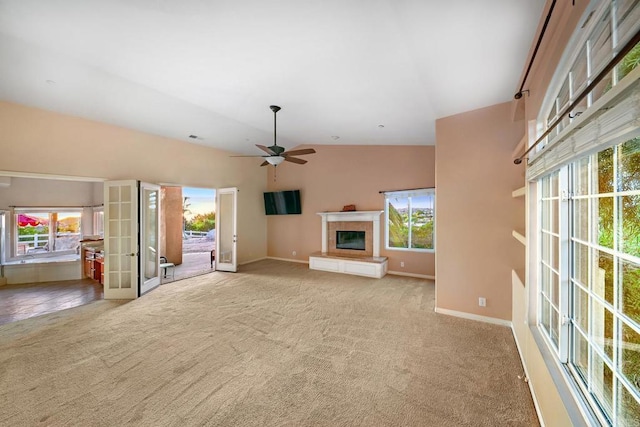 unfurnished living room featuring light carpet, vaulted ceiling, plenty of natural light, and french doors