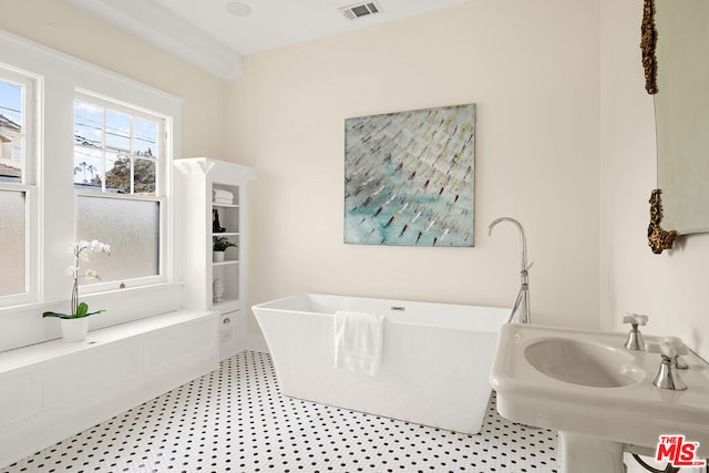 bathroom with a washtub, tile patterned floors, and sink