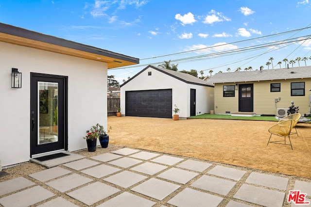 view of patio / terrace with ac unit, a garage, and an outbuilding