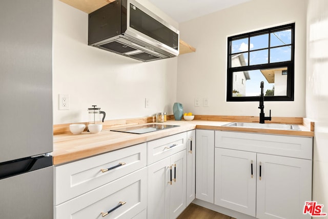 kitchen with white cabinetry, sink, wooden counters, wood-type flooring, and appliances with stainless steel finishes