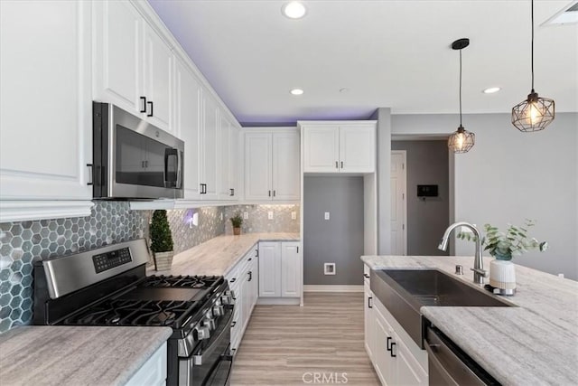 kitchen with white cabinetry, sink, stainless steel appliances, light stone counters, and light hardwood / wood-style floors