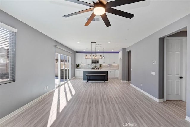 unfurnished living room with light hardwood / wood-style floors, plenty of natural light, and ceiling fan