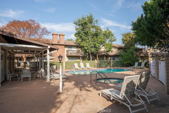 pool featuring a community hot tub, a patio, and fence