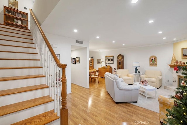 living room with recessed lighting, visible vents, light wood finished floors, and stairs