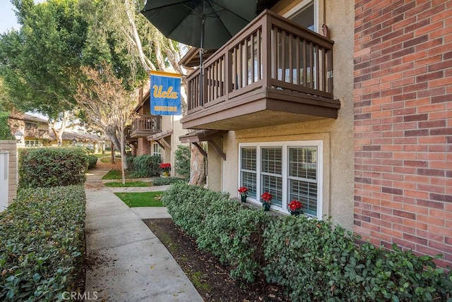 exterior space featuring brick siding, a balcony, and stucco siding