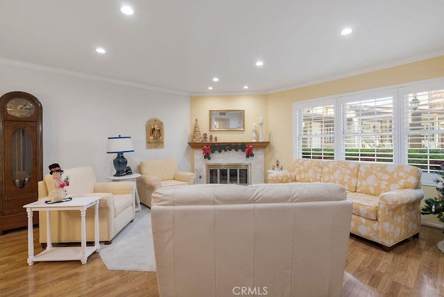 living room with ornamental molding, wood finished floors, and a glass covered fireplace