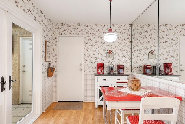 dining room featuring light wood-type flooring and wallpapered walls