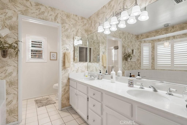 bathroom featuring double vanity, tile patterned flooring, a sink, and wallpapered walls