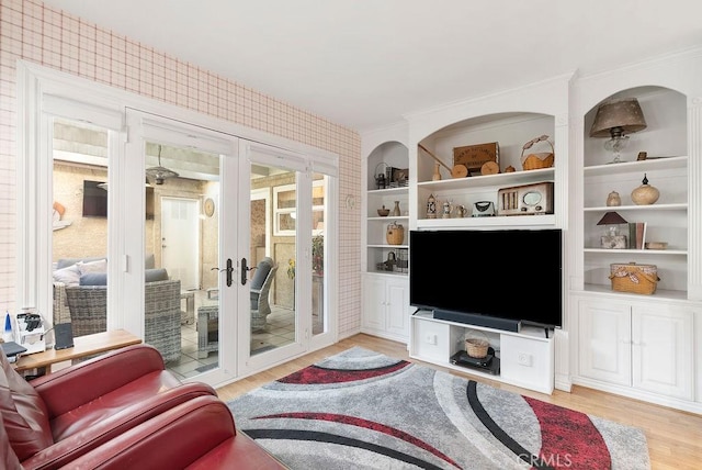 living area featuring light wood-type flooring, crown molding, and french doors