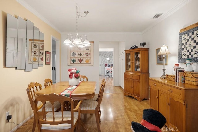 dining space featuring baseboards, visible vents, an inviting chandelier, crown molding, and light wood-style floors