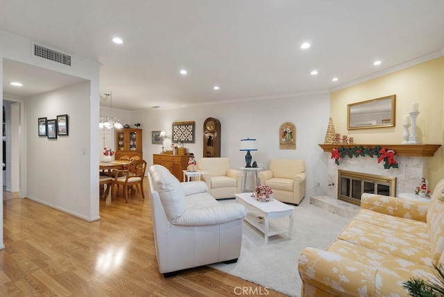 living area featuring visible vents, light wood-style flooring, ornamental molding, a fireplace, and recessed lighting