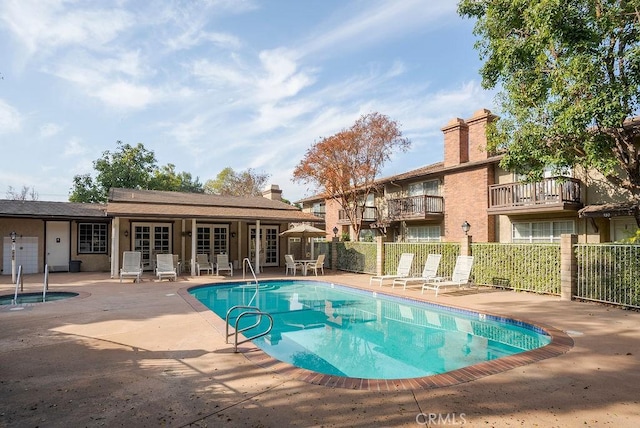 community pool featuring fence, a patio, and french doors