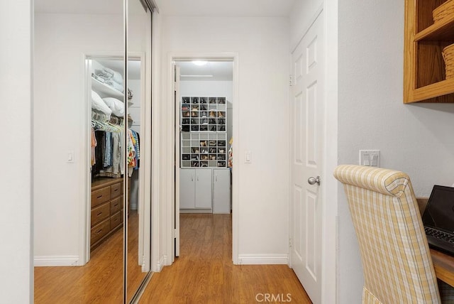 hall featuring light wood-type flooring and baseboards