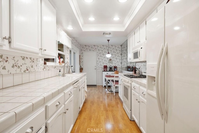 kitchen with visible vents, a tray ceiling, white appliances, and tile counters