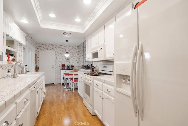 kitchen featuring white appliances, visible vents, tile countertops, a tray ceiling, and a sink