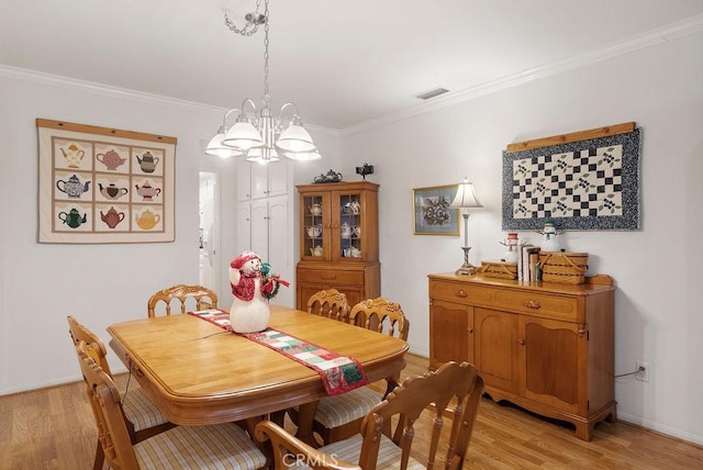 dining area with a chandelier, light wood-type flooring, visible vents, and crown molding