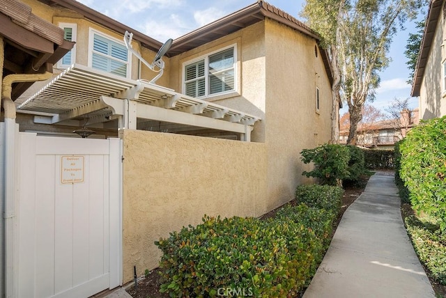 view of home's exterior featuring stucco siding, fence, and a pergola