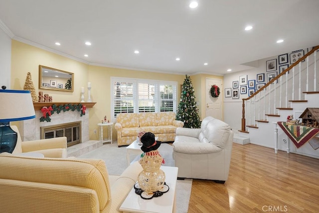 living room with a fireplace, recessed lighting, ornamental molding, wood finished floors, and stairs