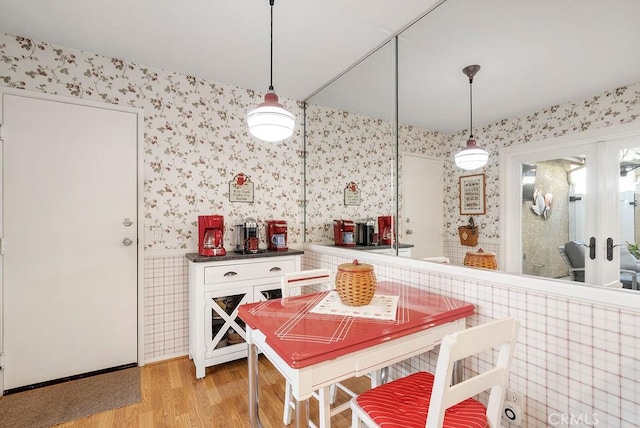 dining area featuring wallpapered walls, light wood-style floors, and french doors