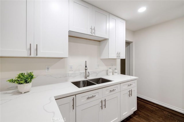 kitchen with white cabinets, light stone counters, sink, and dark wood-type flooring