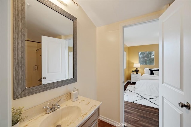 bathroom with hardwood / wood-style floors, vanity, and lofted ceiling