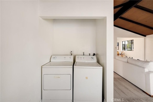 laundry room featuring washer and clothes dryer, light colored carpet, and wood ceiling