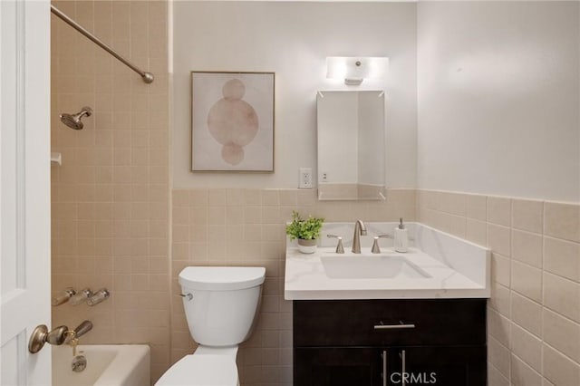 full bathroom featuring vanity, toilet, tile walls, and tiled shower / bath combo