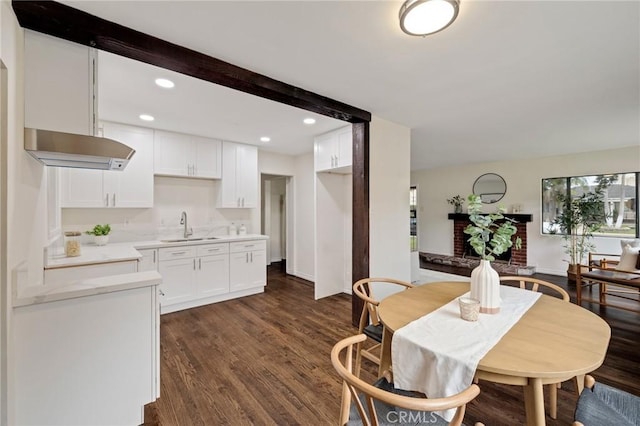 dining area featuring beam ceiling, sink, and dark wood-type flooring