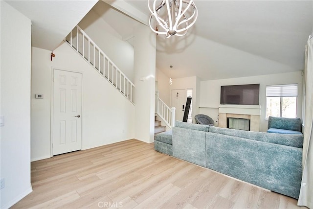 living room featuring a fireplace, high vaulted ceiling, a notable chandelier, and light wood-type flooring