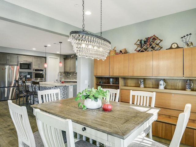 dining room featuring sink, dark wood-type flooring, and an inviting chandelier