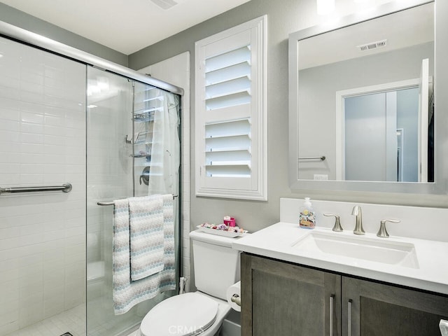 bathroom with vanity, toilet, and a shower with shower door