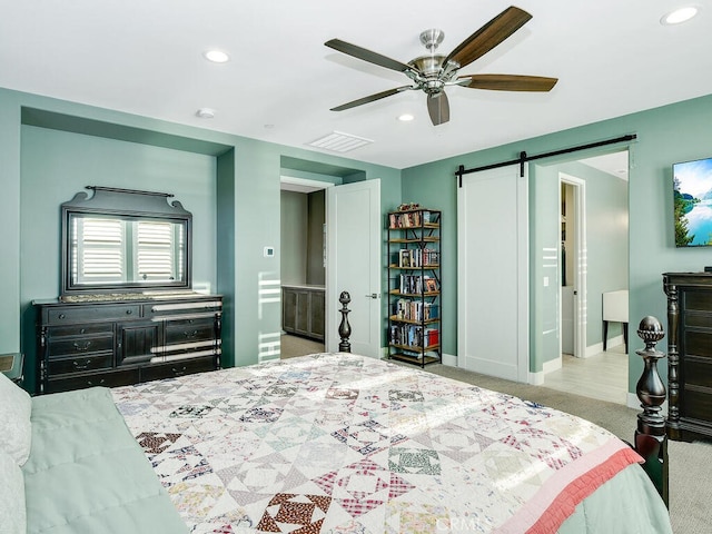 carpeted bedroom with ceiling fan, a barn door, and ensuite bath