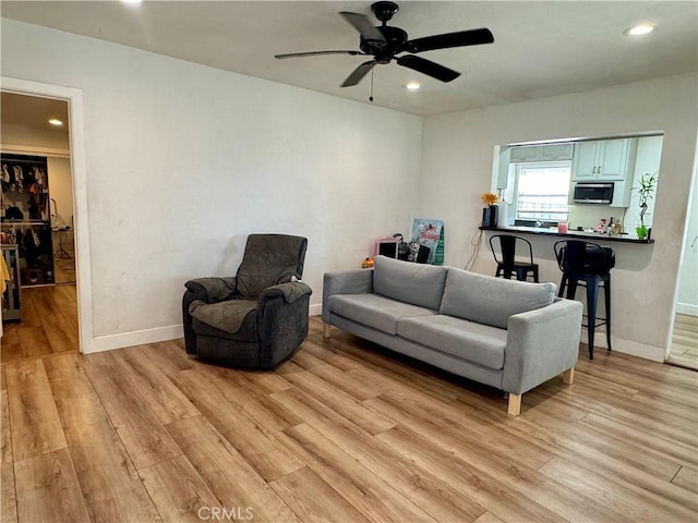 living room with ceiling fan and light hardwood / wood-style flooring