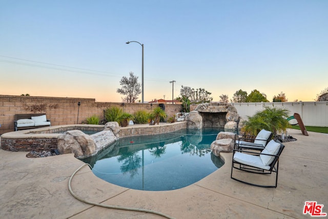 pool at dusk featuring an in ground hot tub