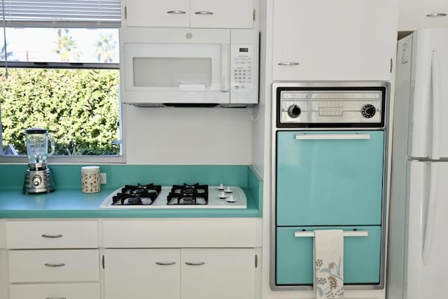 kitchen with a wealth of natural light, white cabinets, and white appliances