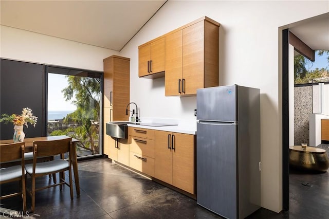 kitchen with stainless steel fridge, a healthy amount of sunlight, sink, and vaulted ceiling