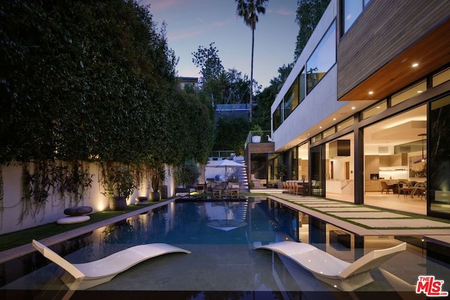 pool at dusk with a patio