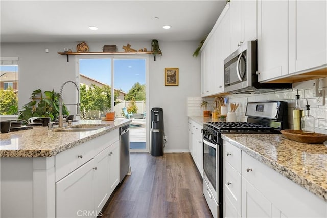 kitchen featuring stainless steel appliances, light stone countertops, sink, and white cabinets