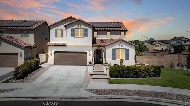 mediterranean / spanish-style home with a garage, a lawn, and solar panels