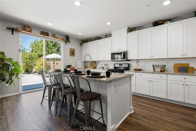 kitchen with white cabinetry, appliances with stainless steel finishes, and an island with sink