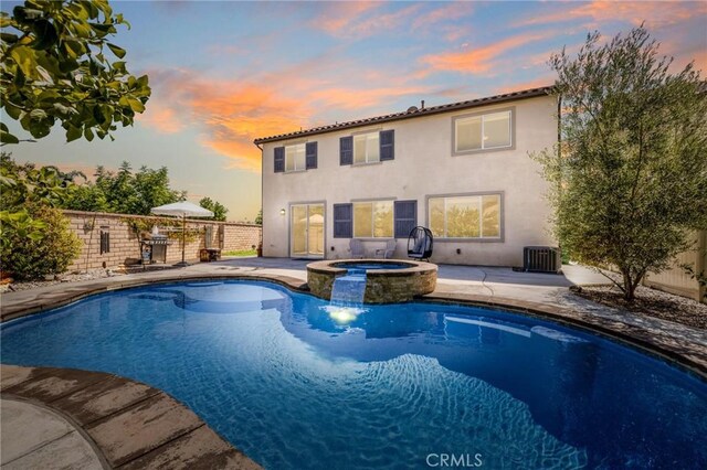 pool at dusk featuring central AC unit, an in ground hot tub, and a patio