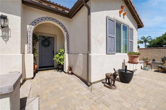 view of exterior entry with a patio area