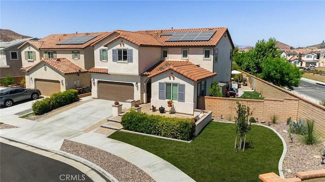 mediterranean / spanish home featuring a garage, a front lawn, and solar panels