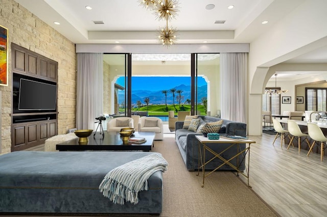 living room with a raised ceiling and light hardwood / wood-style flooring