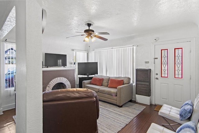 living room featuring a textured ceiling, ceiling fan, and dark wood-type flooring