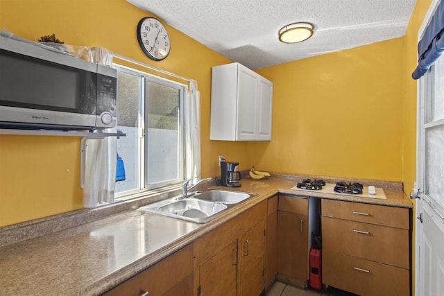 kitchen with a textured ceiling, white cabinetry, and sink