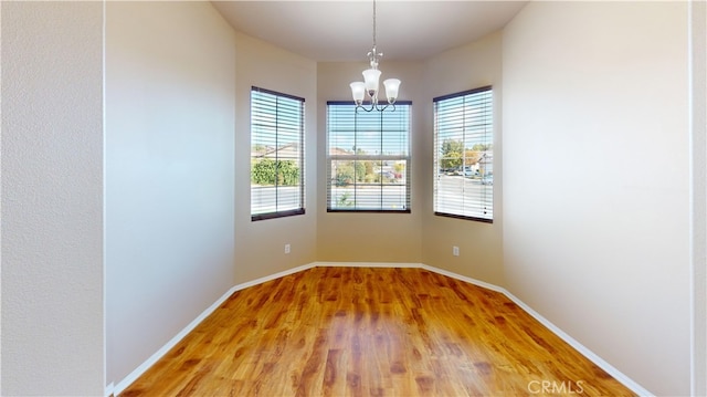 spare room featuring an inviting chandelier and wood-type flooring