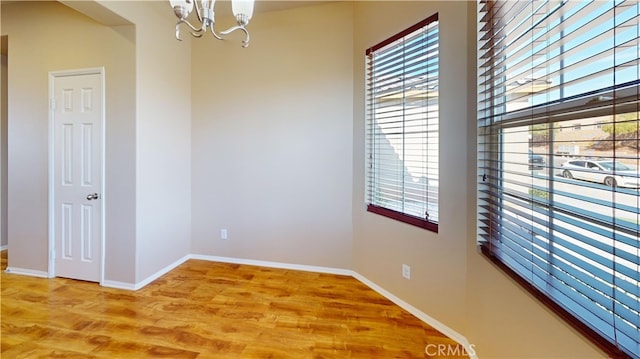 spare room featuring hardwood / wood-style flooring, a chandelier, and a healthy amount of sunlight