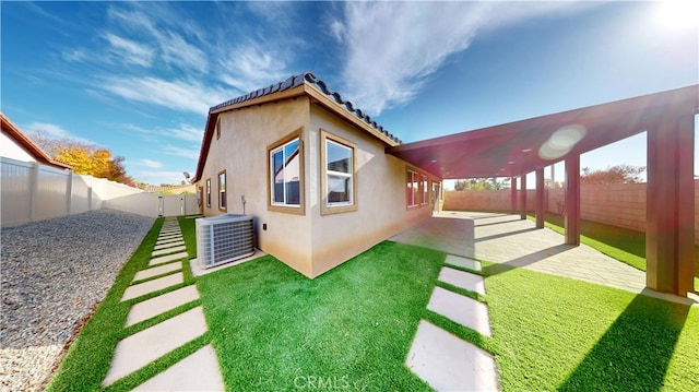 back of property featuring a patio area, a lawn, and central AC